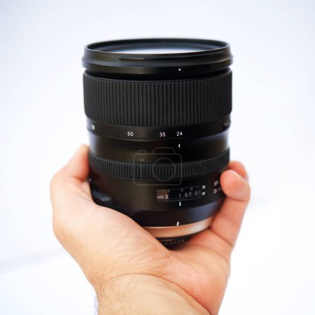 Person Showing sixty milimeters lens in the hand with isolated white backdrop. Close up of Camera lens in the hand of a person