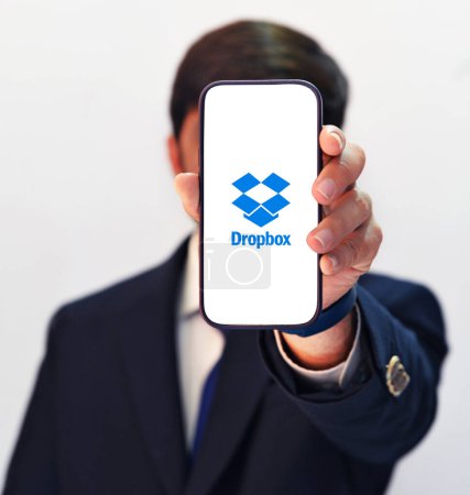Photo for Professional Man showing Dropbox on the mobile screen with white isolated background, editorial - Royalty Free Image