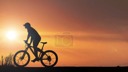Téléchargez les photos : Silhouette de cycliste faisant de l'exercice dans la prairie le soir, concept de soins de santé fitness - en image libre de droit