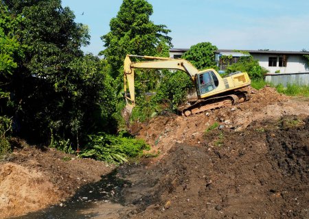 Téléchargez les photos : Excavatrice sur un chantier. excavatrice dans le sol. Excavatrice creusant des canaux obstrués pour drainer l'eau avant la saison des pluies. - en image libre de droit