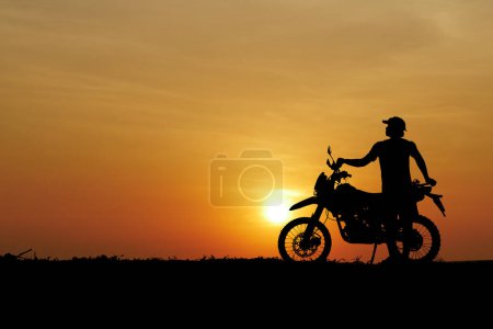 Téléchargez les photos : Homme avec moto-cross contre le coucher du soleil dans le domaine - en image libre de droit