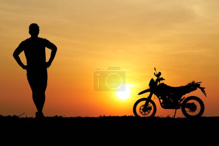 Foto de Hombre con moto de motocross contra puesta de sol en el campo - Imagen libre de derechos