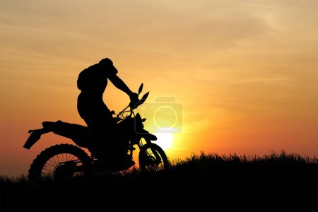 Téléchargez les photos : Homme avec moto-cross contre le coucher du soleil dans le domaine - en image libre de droit