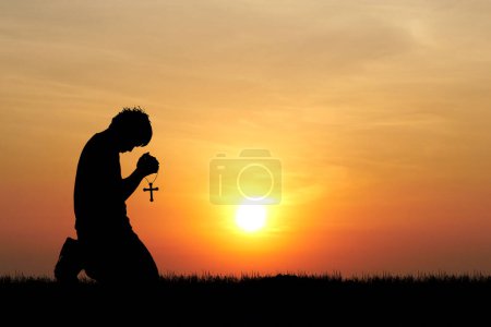 Téléchargez les photos : Priant homme avec croix sur le fond de la nuit étoilée - en image libre de droit