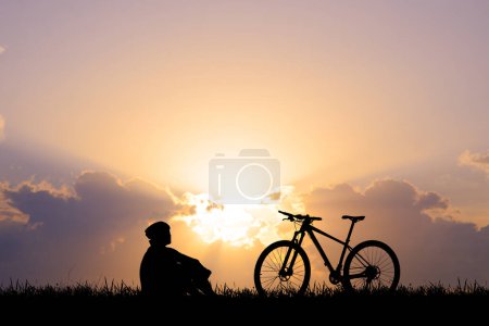 Téléchargez les photos : Silhouette de cycliste faisant de l'exercice dans la prairie le soir, concept de soins de santé fitness - en image libre de droit