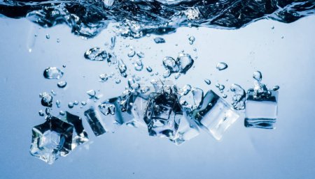 Foto de Cubos de hielo cayendo en el agua que se hunde hasta el fondo. Fondo abstracto
. - Imagen libre de derechos