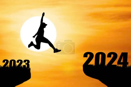 Téléchargez les photos : Silhouette d'homme au coucher du soleil sautant de 2023 à 2024. - en image libre de droit