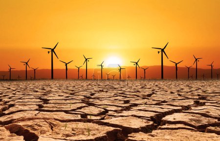 Photo for Wind turbines in a dry land on orange sky background, global warming concept - Royalty Free Image