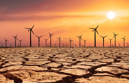 Photo for Wind turbines in a dry land on orange sky background, global warming concept - Royalty Free Image