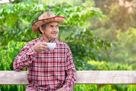 asian senior man business owner sitting in his coffee farm , older adult coffee farmer in checkered shirt relaxing with coffee cup in hand , concept elderly people lifestyle, activity, work, relaxing