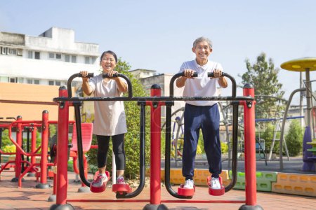 Foto de Asiático senior pareja haciendo ejercicio en gimnasio máquina en parque, concepto para ancianos estilo de vida, al aire libre actividad, entrenamiento, recreación - Imagen libre de derechos