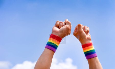 hombre manos lleva lgbtq colorido arco iris pulsera haciendo puño de la mano hacia el cielo, el apoyo o el respeto de lgbtq + movimiento de igualdad comunitaria, amor, derechos, libertad, tolerancia, concepto lgbt feliz orgullo mes