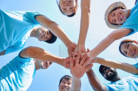bajo ángulo, grupo de personas felices diversidad sonrisa, apilar las manos para apoyar, confianza, ayuda, éxito para el compromiso de caridad voluntaria mientras se trabaja al aire libre