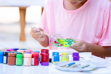 Photo for Asian teens boy concentrate on painting in school art club, mixing the watercolors in the palette on table, concept of school elective activities, art talent ability - Royalty Free Image