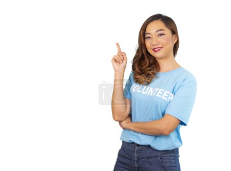 lächelnde junge asiatische Aktivistin trägt freiwilliges blaues T-Shirt, zeigt mit der Hand auf Kopierplatz für Text auf blauem Hintergrund, Konzept der freiwilligen Charity-Kampagne