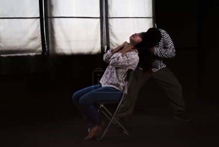 Téléchargez les photos : Scene of a thief strangled victim that sat on chair in the dark room,concept of women victim,hostage,crime,violence - en image libre de droit