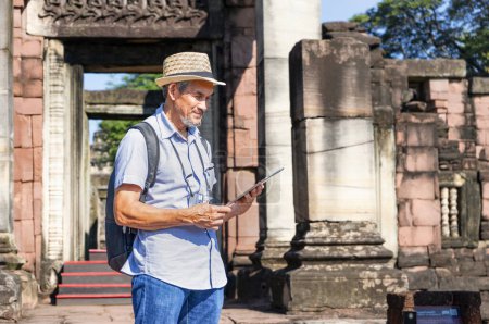 senior homme portant chapeau avec sac à dos, appareil photo et tablette en main est la recherche de données à l'ancien site archéologique.concept tourisme sites anciens, archéologue, travail d'archéologie