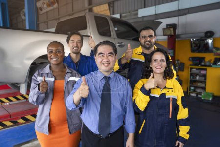 multiracial auto service teamwork led by asian senior man business owner standing at his shop and doing thumbs up together, garage service