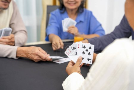 group of active senior pensioners playing cards game together, concept elderly retired people entertainment,recreation,encourages social interaction,help memory retention 
