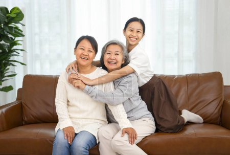 retrato feliz familia abuela y nieta sentado en el sofá en la sala de estar, sonriendo y mirando a la cámara