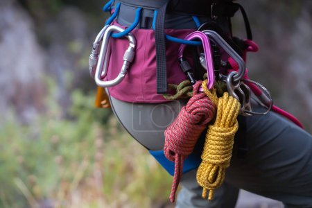 Equipo de escalada, cuerdas, mosquetones, arnés, cinturón, primer plano de un escalador de roca puesto por una chica, el viajero lleva un estilo de vida activo y se dedica al montañismo.