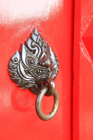Photo for Close up red door - Freshly painted red front door with mythical creature head bronze knocker - Royalty Free Image