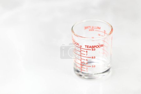 Téléchargez les photos : Tasse de mesure en verre ou tasse doseuse avec des mesures de cuillère à café affichées. - en image libre de droit