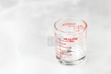 Téléchargez les photos : Glass measuring cup or dosage cup with millilitre measurements displayed. - en image libre de droit
