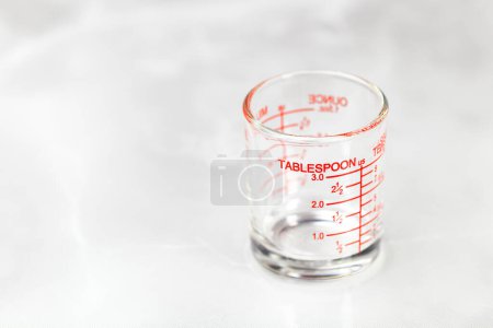 Téléchargez les photos : Tasse de mesure en verre ou tasse doseuse avec des mesures de cuillère à soupe affichées. - en image libre de droit