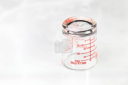 Téléchargez les photos : Tasse de mesure en verre inversé ou tasse doseuse avec des mesures de millilitre affichées. - en image libre de droit