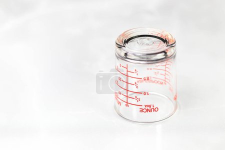 Téléchargez les photos : Tasse de mesure en verre inversé ou tasse doseuse avec mesures d'once affichées. - en image libre de droit