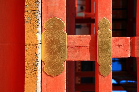 Antique decorative golden stake on red wooden gate of ancient japan temple.