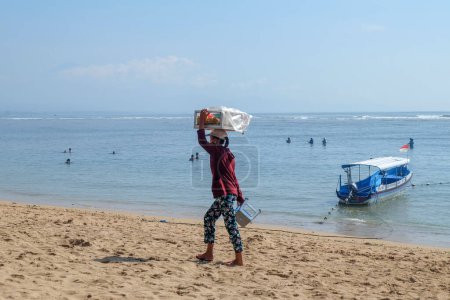 Téléchargez les photos : Sanur, Bali, Indonésie - 7 février 2021 : activités de commerce de colporteurs sur la plage de Sanur. Ils vendent des aliments traditionnels appelés "Lumpia"" - en image libre de droit