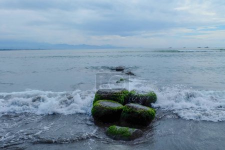 Téléchargez les photos : Rochers au milieu de la plage (mer) et une tour au bout de la plage. La pierre utilisée pour marcher les pêcheurs. - en image libre de droit