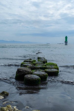 Téléchargez les photos : L'atmosphère le matin à Matahari Terbit Beach, Sanur, Bali, Indonésie. Il y a des vagues qui s'écrasent contre des rochers, des bateaux de pêche et des tours de guet. Le rocher sur lequel reposent les pêcheurs - en image libre de droit
