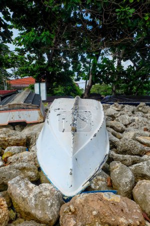 Téléchargez les photos : L'ancienne coque d'un bateau (bateau de pêche) échoué sur un tas de rochers de plage. - en image libre de droit