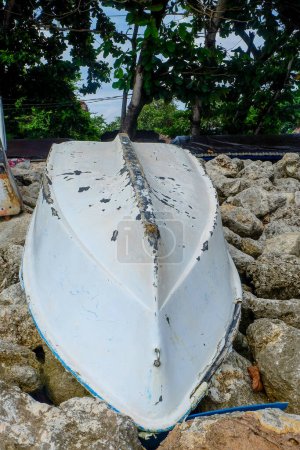 Téléchargez les photos : L'ancienne coque d'un bateau (bateau de pêche) échoué sur un tas de rochers de plage. - en image libre de droit