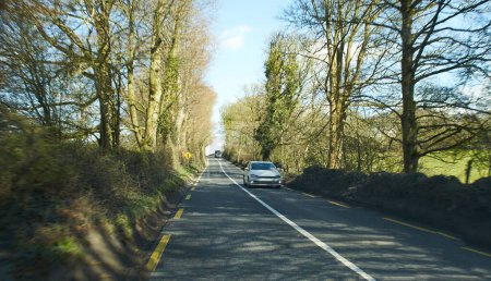 Téléchargez les photos : Vue arrière de voitures conduisant sur autoroute, Irlande. Route avec barrière de sécurité métallique ou rail. voitures sur l'asphalte sous le ciel bleu nuageux. Trafic routier. - en image libre de droit