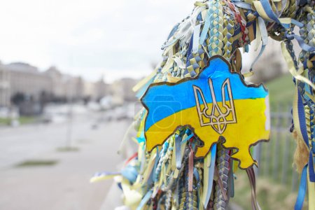 Photo for Yellow and blue ribbons symbolize the Ukrainian flag in honour of the Heroes of Territorial Defence who died in Ukraine. Independence Square on background - Royalty Free Image