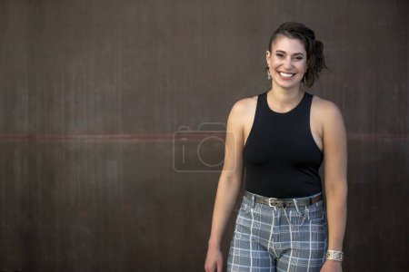 Photo for Portrait of a unique and stylish artist, standing in front of a large rustic metal wall, copy space - Royalty Free Image