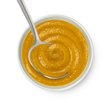Pumpkin cream soup with spoon isolated on white background. Top view