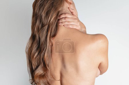 Téléchargez les photos : Femme nue avec douleur dans le cou et le dos sur fond blanc. Vue arrière
. - en image libre de droit
