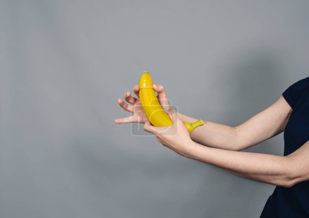 Téléchargez les photos : Les mains de la femme mettent un préservatif sur la banane. Sexe protégé. - en image libre de droit