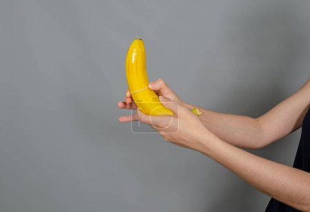 Téléchargez les photos : Les mains de la femme mettent un préservatif sur la banane. Le sexe protégé. Prévention de la grossesse. - en image libre de droit