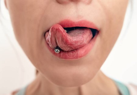 Foto de Primer plano de la boca de la mujer con la lengua sobresaliendo. Perforación en la lengua de la mujer. - Imagen libre de derechos