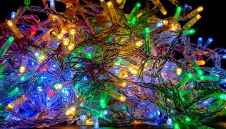 Téléchargez les photos : Guirlandes de nouvel an colorées avec des lampes LED sont laissées tomber de manière chaotique. Décor du Nouvel An, fond - en image libre de droit