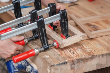 Foto de Abrazaderas de carpintería sujetaban un marco de madera en un taller de carpintería - Imagen libre de derechos