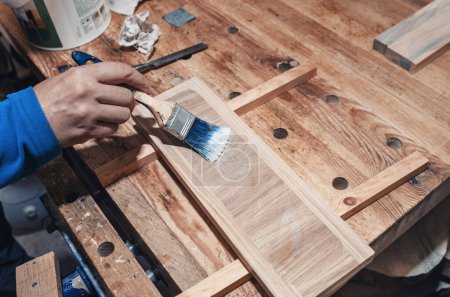 Foto de Barnizar un cajón de madera, taller de carpintería. El barniz se aplica a una tabla de madera con un cepillo - Imagen libre de derechos