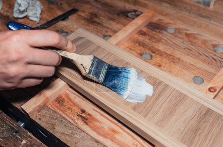 Foto de Barnizar un cajón de madera, taller de carpintería. El barniz se aplica a una tabla de madera con un cepillo - Imagen libre de derechos