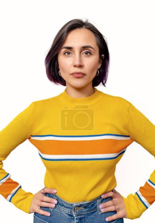 Foto de Mujer tranquila seria confiada que usa suéter amarillo aislado sobre fondo blanco. Manos en la cintura. - Imagen libre de derechos